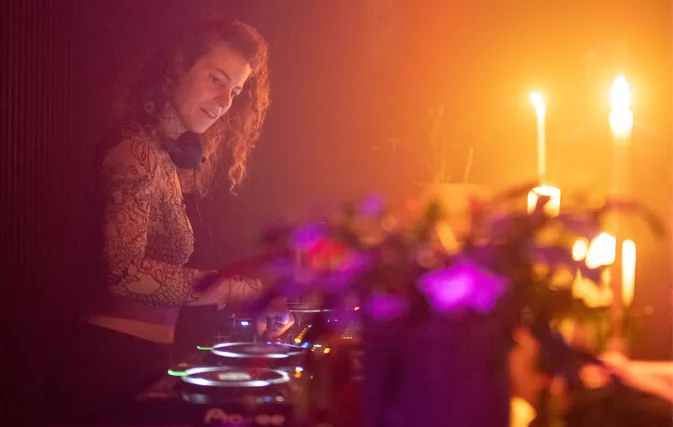 Nora Milena am DJ-Pult, im warmen Licht mit Kerzen